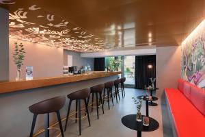 a bar in a restaurant with a red couch and stools at VISIONAPARTMENTS Basel Nauenstrasse - contactless check-in in Basel