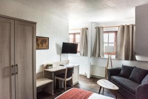ein Wohnzimmer mit einem Sofa und einem Schreibtisch in einem Zimmer in der Unterkunft Hotel Up´n Diek in Dangast