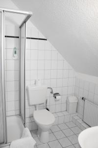 a white bathroom with a toilet and a shower at Hotel Up´n Diek in Dangast