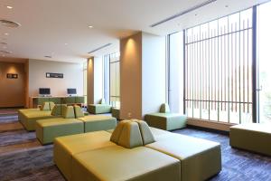 a waiting room with yellow couches and large windows at Ooedo Onsen Monogatari Beppu Seifu in Beppu