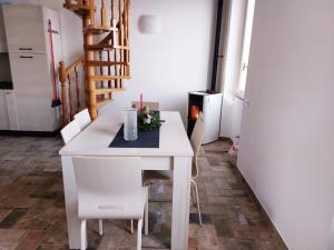 a dining room with a white table and white chairs at Casa ORI in Perledo