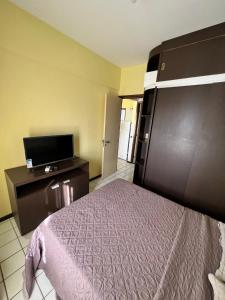 um quarto de hotel com uma cama e uma televisão de ecrã plano em Navegantes apartamento no Recife