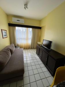 uma sala de estar com um sofá e uma televisão em Navegantes apartamento no Recife