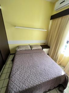um quarto com uma cama com um edredão roxo e uma janela em Navegantes apartamento no Recife