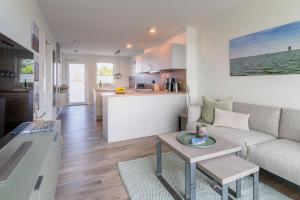 a living room and kitchen with a couch and a table at Ferienwohnung Ankergold in Nordstrand