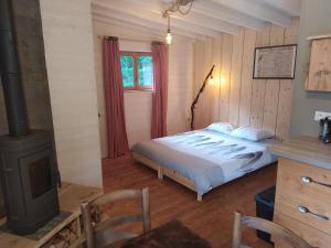 een slaapkamer met een bed en een houtkachel bij Gîte nature Au pied des hêtres in Vitrac-sur-Montane
