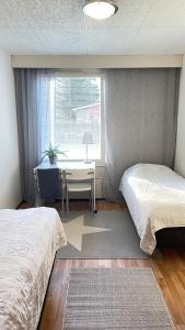 a bedroom with two beds and a desk and a window at Omakotitalo 100m2, 3 makuuhuonetta Joensuu in Joensuu