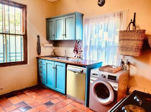 a kitchen with blue cabinets and a washing machine at Elizabeth's Cottage in Montagu