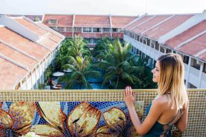 a woman standing on the ledge of a building with a mosaic wall at Almanity Hoi An Resort & Spa in Hoi An
