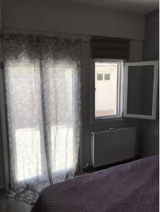 a bedroom with a bed and two windows with curtains at Country House in Pachia Ammos