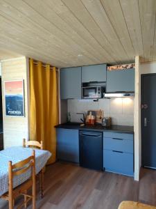 una cocina con armarios azules y una mesa en una habitación en Appartement confort et style en pied de piste en Bolquere Pyrenees 2000