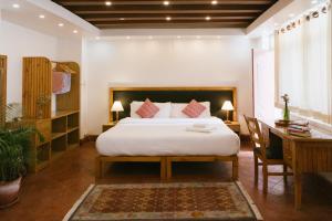 a bedroom with a bed and a desk and a bed sidx sidx sidx at Tajaa Pha The Heritage Home in Pātan +28 photos