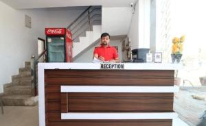 a man is standing behind a reception desk at Ganga Guest House By WB Inn in Agra