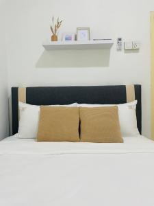 łóżko z białymi poduszkami i czarnym zagłówkiem w obiekcie Chenang's Guest House by The Nordic House w mieście Pantai Cenang