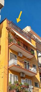 un bâtiment jaune avec une flèche sur son côté dans l'établissement Casa-B&B Bouganville Attico 85 mq, à Barletta