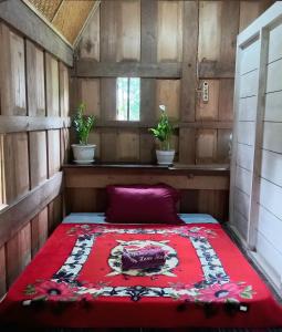 Una cama en una habitación con una manta roja. en Toraja Homestay & Coffee Bunna, en Rantepao
