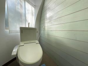 a white toilet in a bathroom with a wooden wall at Seiryukyou in Nishinoomote