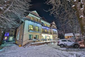 een auto geparkeerd voor een gebouw in de sneeuw bij Parkowy Dworek in Rabka