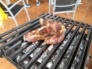 un pedazo de carne está cocinando en una parrilla en La Casona de Soviña, en Piloña