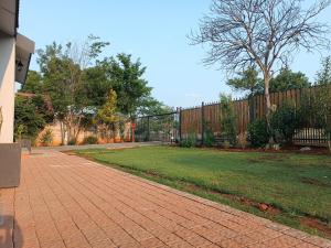 een stenen loopbrug in een tuin met een hek bij Nini's guest units in Bloemfontein