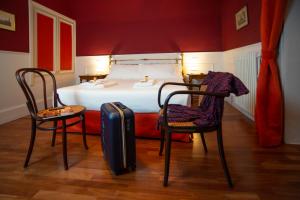 a bedroom with a bed with two chairs and a suitcase at I Sogni della Memoria in Ragusa