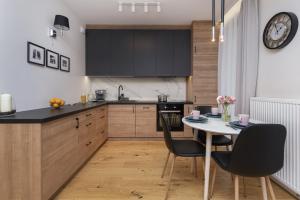 Gdańsk Vespa Apartment by Renters في غدانسك: مطبخ به دواليب سوداء وطاولة وكراسي