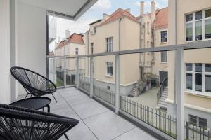 a balcony with two chairs and a view of buildings at Gdańsk Vespa Apartment by Renters in Gdańsk
