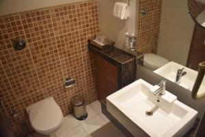 a bathroom with a white sink and a toilet at Royal Orchid Central, Shimoga in Shimoga