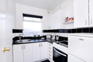 cocina blanca con fregadero y ventana en City view, bright & cozy - Free parking (A4), en Reikiavik