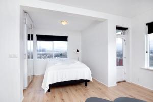 a white bedroom with a bed and large windows at City view, bright & cozy - Free parking (A4) in Reykjavík