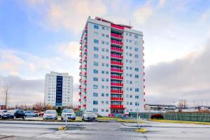 un edificio alto blanco con acentos rojos en un estacionamiento en City view, bright & cozy - Free parking (A4) en Reikiavik