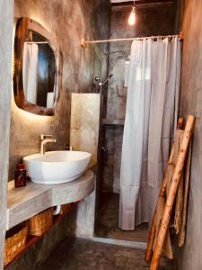 a bathroom with a sink and a mirror and a shower at Helwas Zanzibar Beach Hotel in Bwejuu