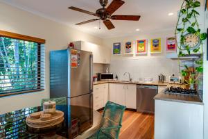 uma cozinha com um frigorífico de aço inoxidável e uma mesa em Tropical Boho Nightcliff Casinha 3BR 1.5BR em Nightcliff