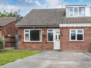 a red brick house with a white door at Ewe Cottage in Ashbourne