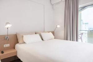 Cama blanca en habitación con ventana en Equador Superior Suites by Olala Homes, en Cascais