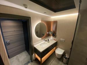 y baño con lavabo, espejo y aseo. en CITY ASYA HOTEL, en Bandırma