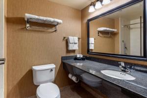 a bathroom with a toilet and a sink and a mirror at Comfort Inn Sturgeon Falls in Sturgeon Falls