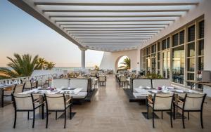 een restaurant op het strand met tafels en stoelen bij Radisson Blu Palace Resort & Thalasso, Djerba in Houmt Souk