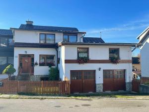 a white house with brown doors and a fence at Sifra 276 in Nová Lesná