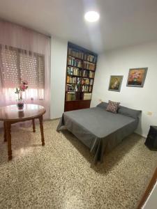 1 dormitorio con cama, mesa y estante de libros en Apartamento en primera línea de playa con piscina. en El Puerto de Santa María