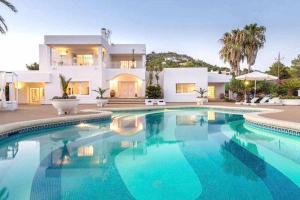 a villa with a swimming pool in front of a house at Gorgeous Villa near Ibiza centre in Santa Eularia des Riu