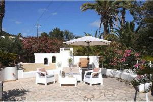 un patio con sillas blancas y una sombrilla en Gorgeous Villa near Ibiza centre, en Santa Eulària des Riu