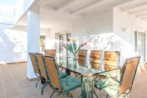 una mesa de cristal con sillas y un jarrón de flores en Gorgeous Villa near Ibiza centre, en Santa Eulària des Riu