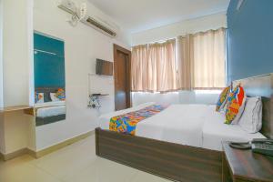 a bedroom with a large bed and a desk and a window at FabExpress Saket Inn in Bhopal
