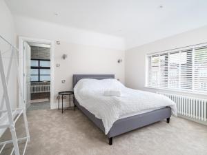 a white bedroom with a bed and two windows at Pass the Keys Luxury 4 Bedroom home with large garden in Watford