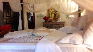 een slaapkamer met een bed met witte lakens en kussens bij African House Resort in Malindi
