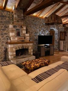 a living room with a stone fireplace and a tv at Villa Ardamis Karyes in Karyes