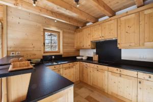 uma cozinha com armários de madeira e um balcão preto em Chalet Lo Villâzo by Mrs Miggins em Grimentz