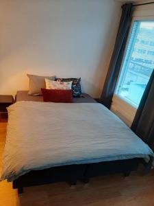 a bed with pillows on it in a room with a window at Cosy apartment in the heart of Lahti, free parking in Lahti