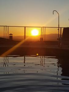 un tramonto su un corpo d'acqua di fronte a una recinzione di El Mirador de Santiago a Monachil